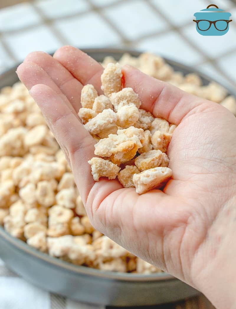 a hand holding up a serving of sugared peanuts.
