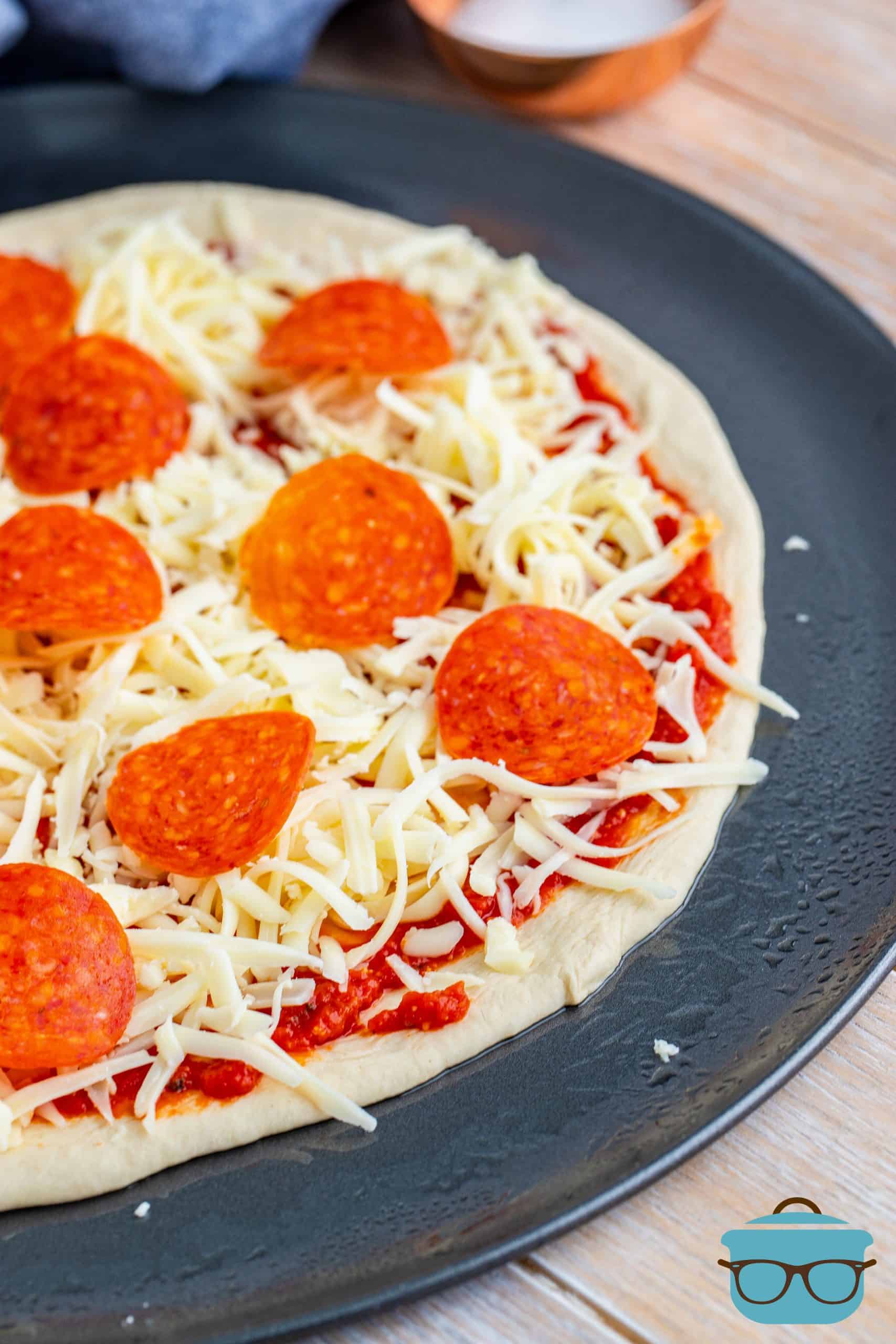 shredded cheese and pepperoni slices on pizza dough.