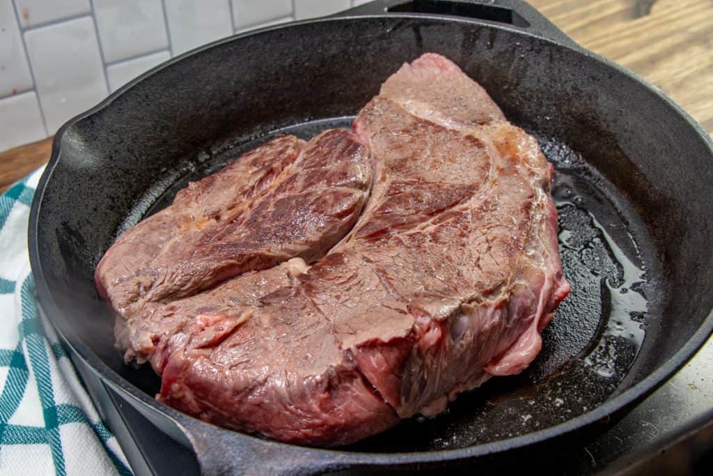 browning a beef chuck roast in a cast iron skillet