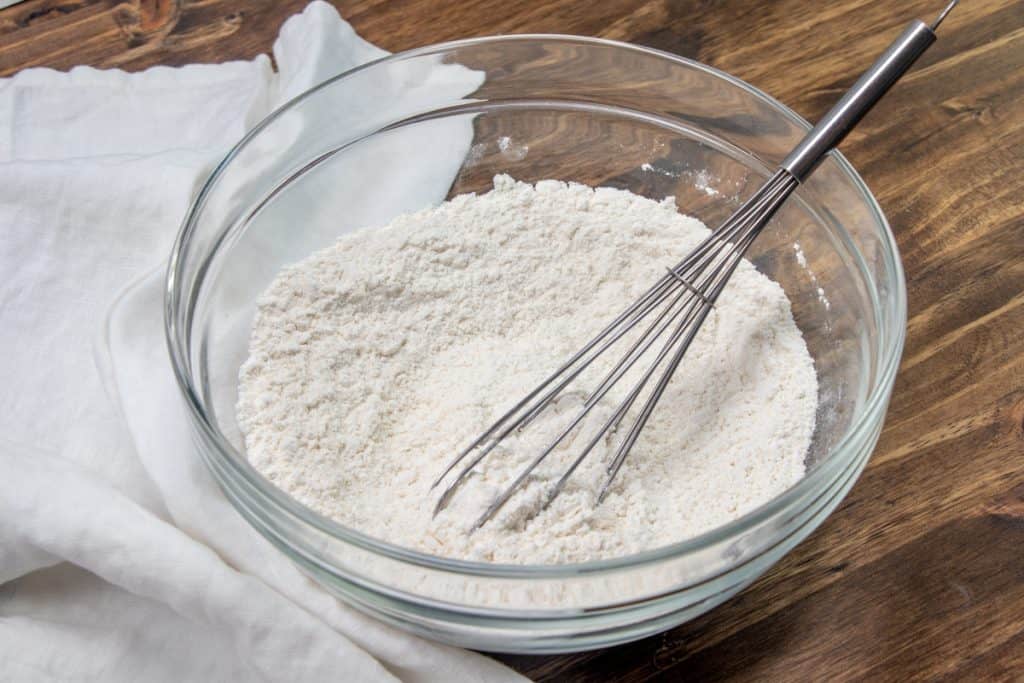 FLOUR, BAKING SODA AND SALT IN A CLEAR BOWL WITH A WHISK