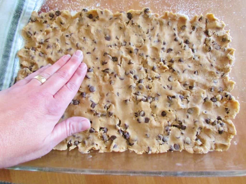 chocolate chip cookie dough spread into a glass Pyrex 9x13 baking dish