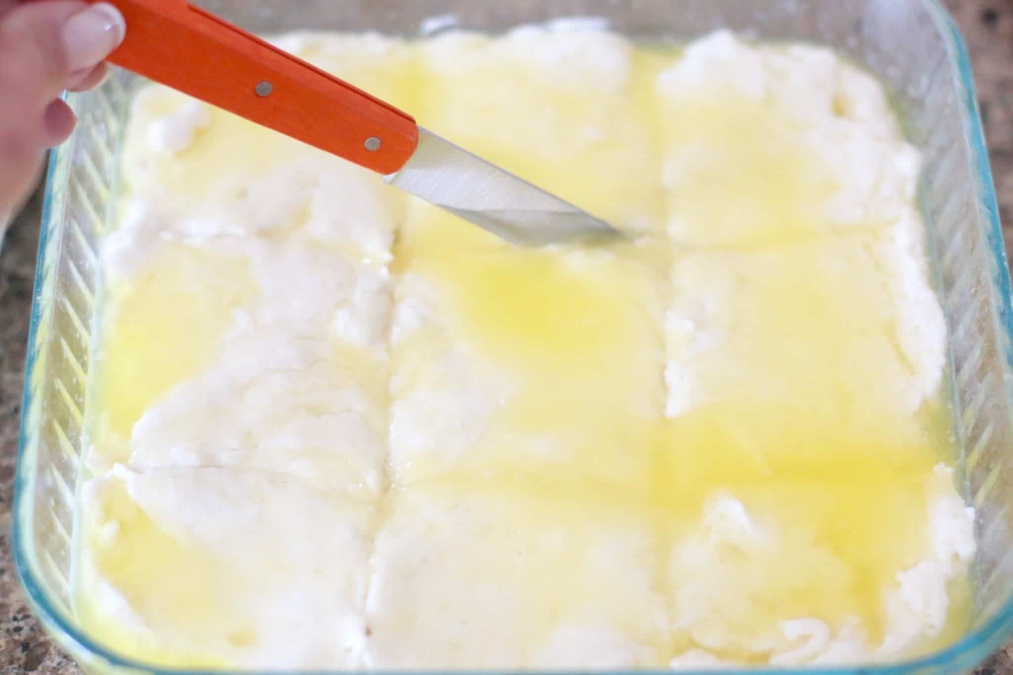 knife cutting through biscuit batter and butter.