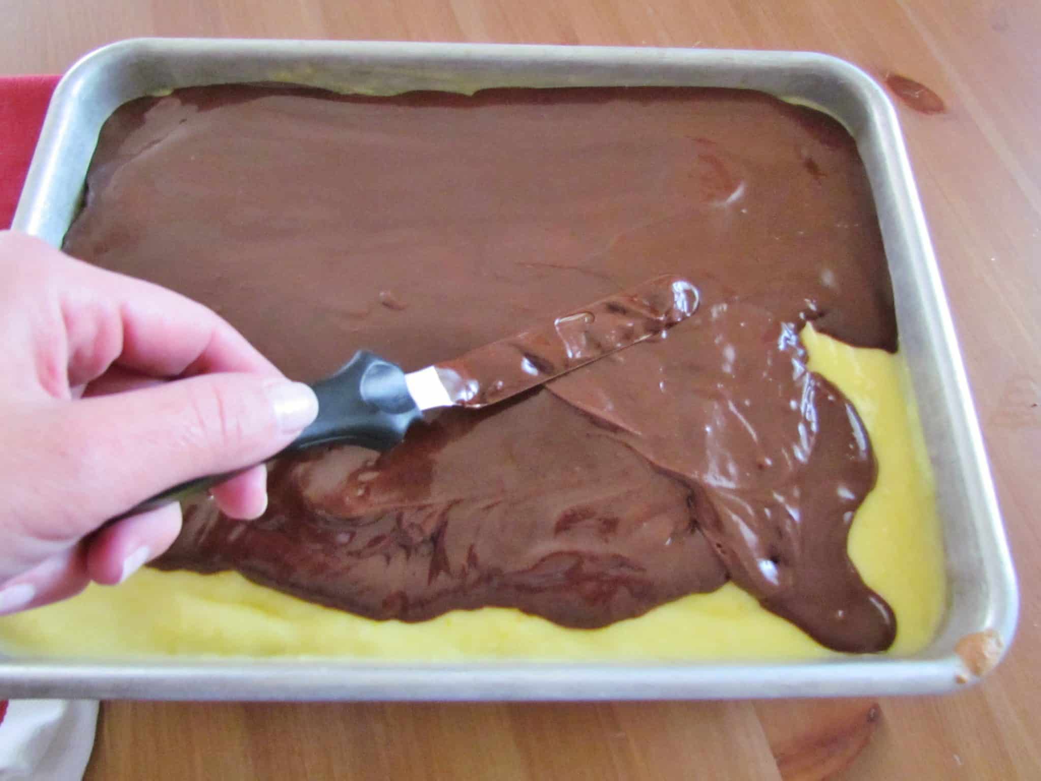 spreading chocolate frosting on top of cake with an offset spatula