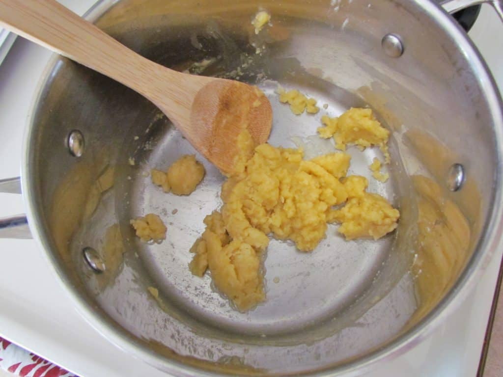 large saucepan holding a mixture of butter and flour with a wooden spoon