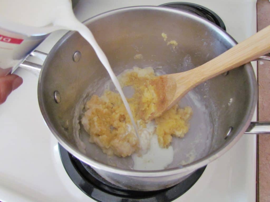 pouring milk into saucepan that contains butter and flour mixture