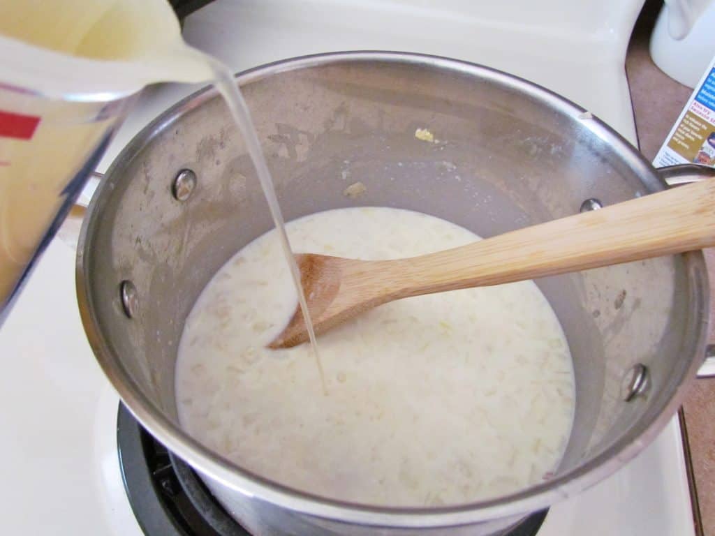 pouring chicken stock into milk, butter and flour mixture in a large saucepan