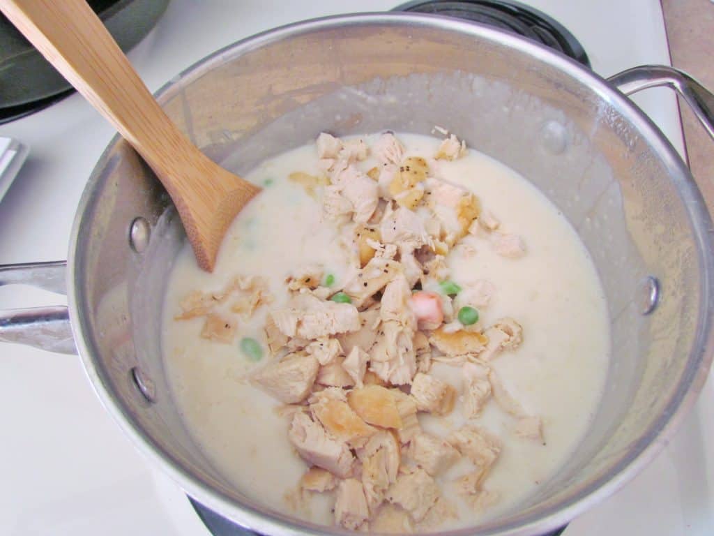 stirring in cooked, diced chicken to saucepan