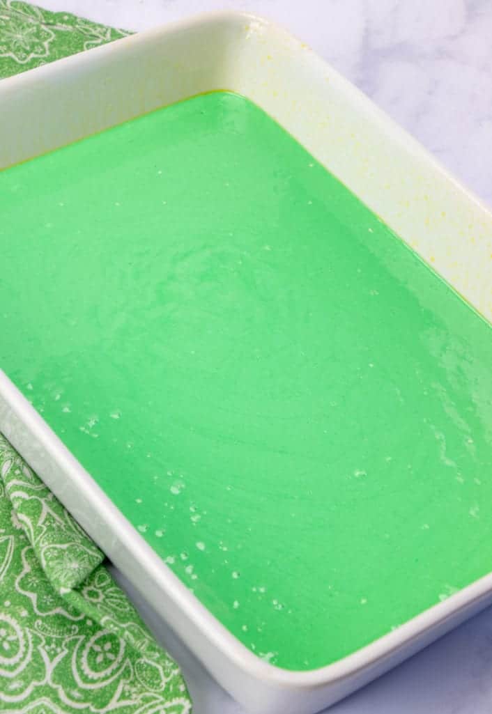 green batter poured into a greased, white 9x13 baking pan