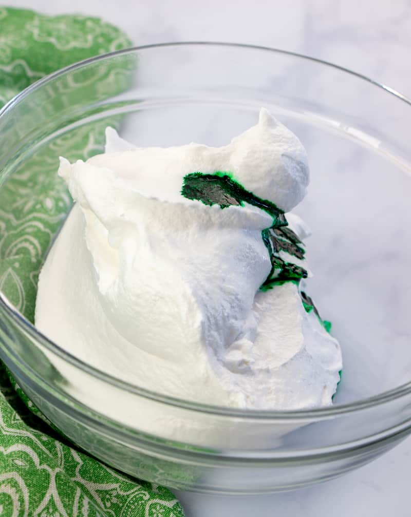 cool whip, mint extract, green food coloring mixed together in a bowl.