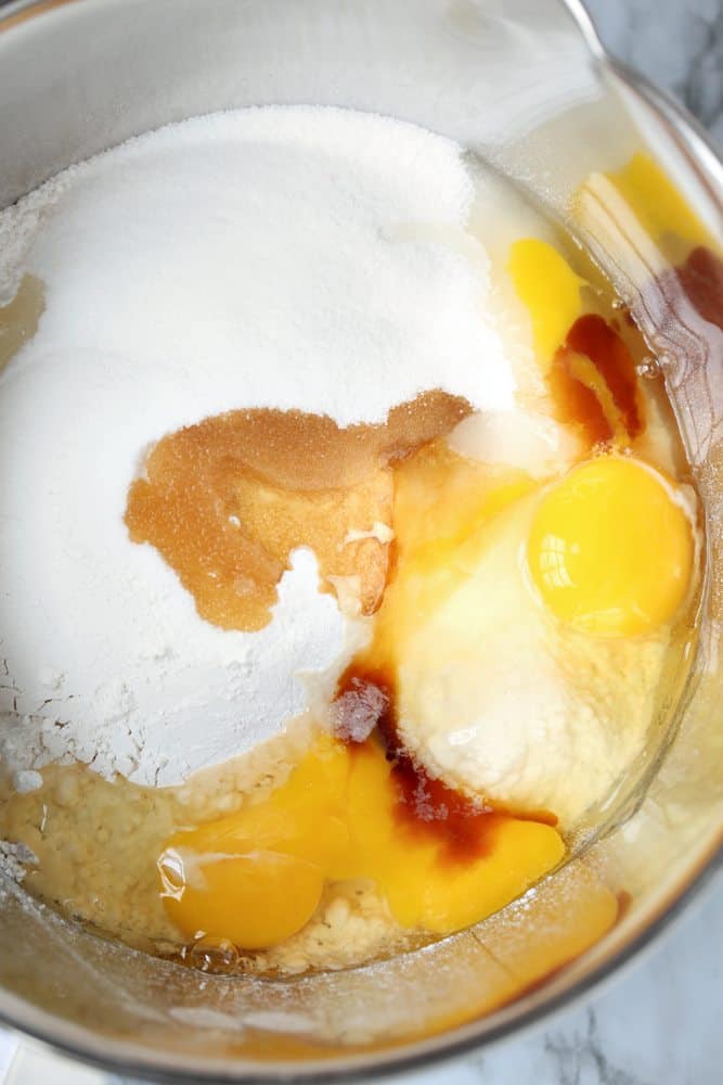 flour, sugar, baking powder, eggs, vanilla shown in a clear glass bowl.