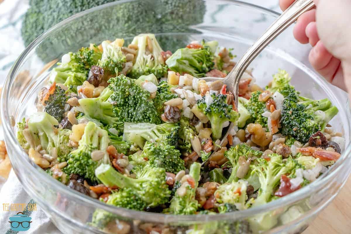 Creamy Broccoli Salad in a clear bowl with silver spoon.