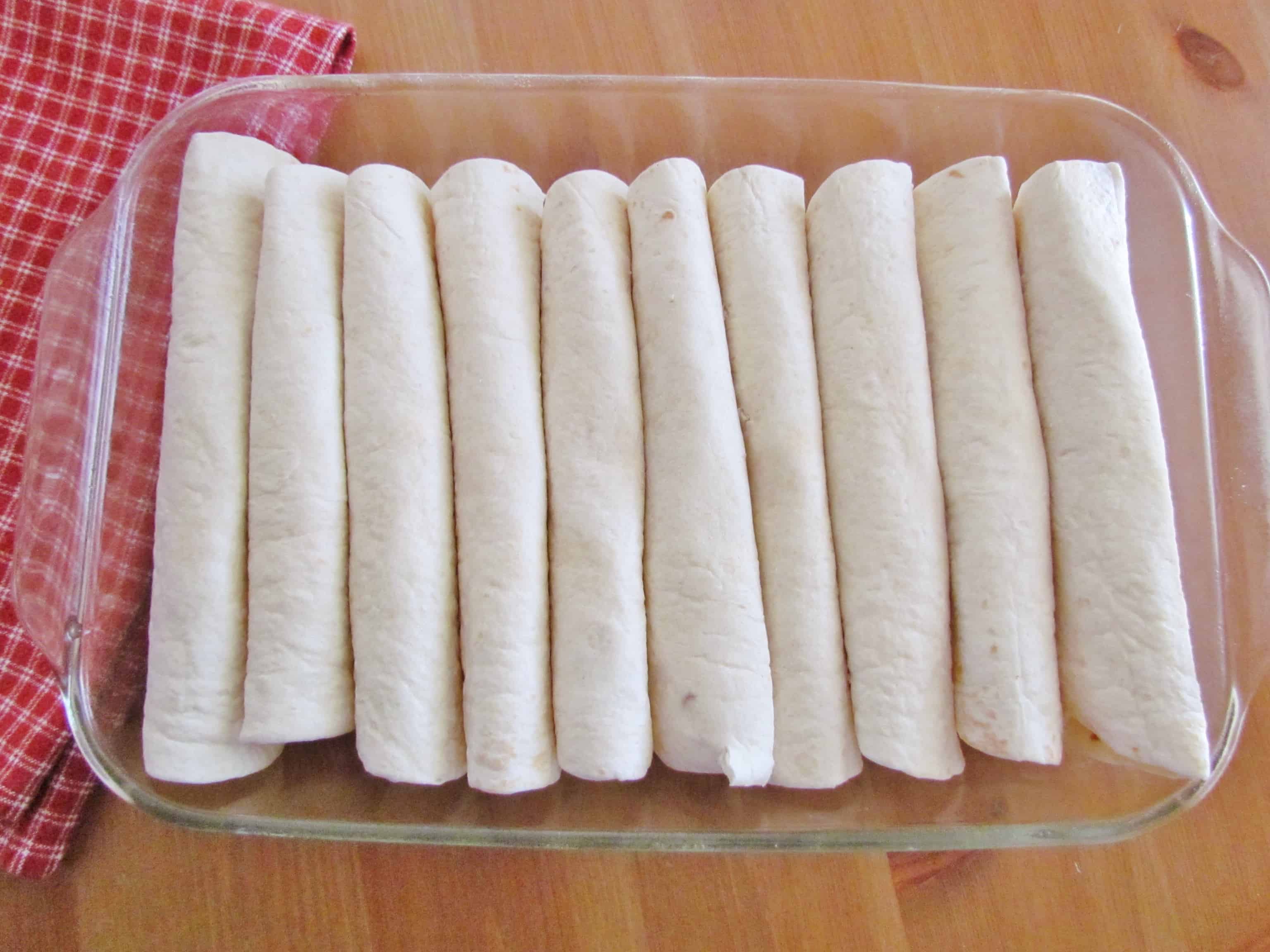 flour tortillas filled with chicken in a baking dish. 