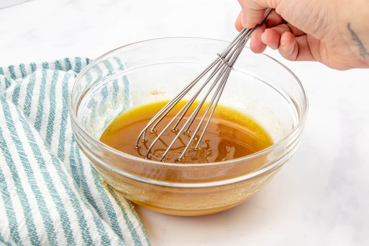 ramen salad dressing mix in a clear bowl with a whisk.