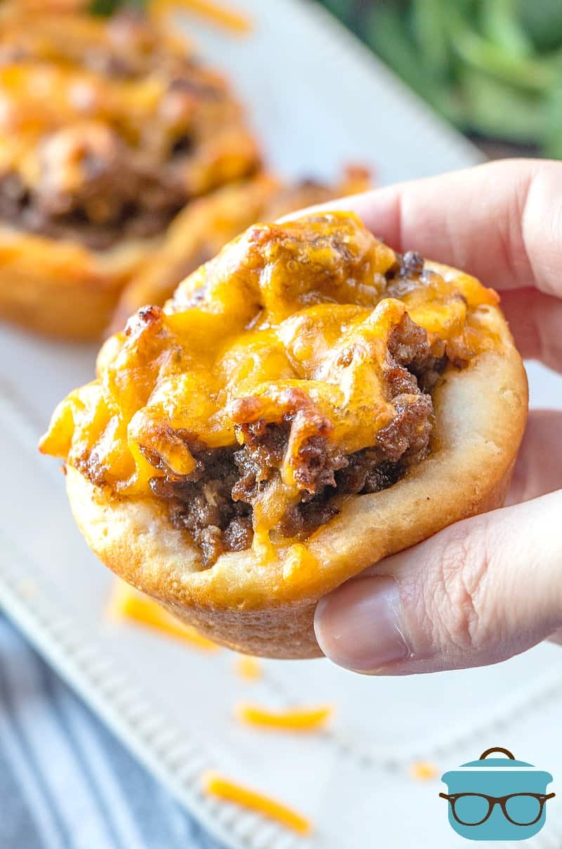 handheld, BBQ Beef Biscuit Cups, easy dinner recipe. hand holding up one of the beef biscuit cups to show it close up. 
