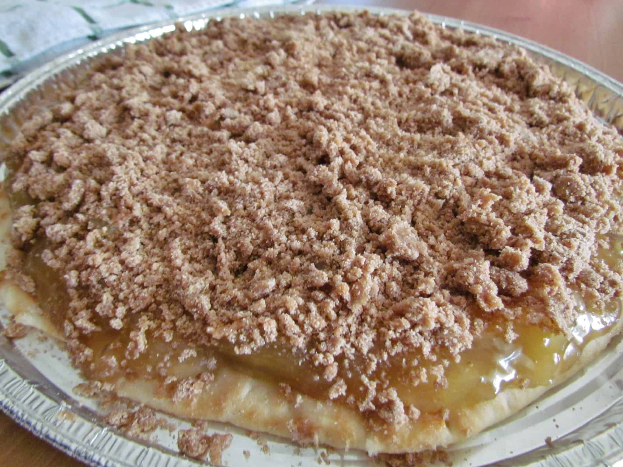 brown sugar crumble topping sprinkled over apple pie filling on pizza crust.