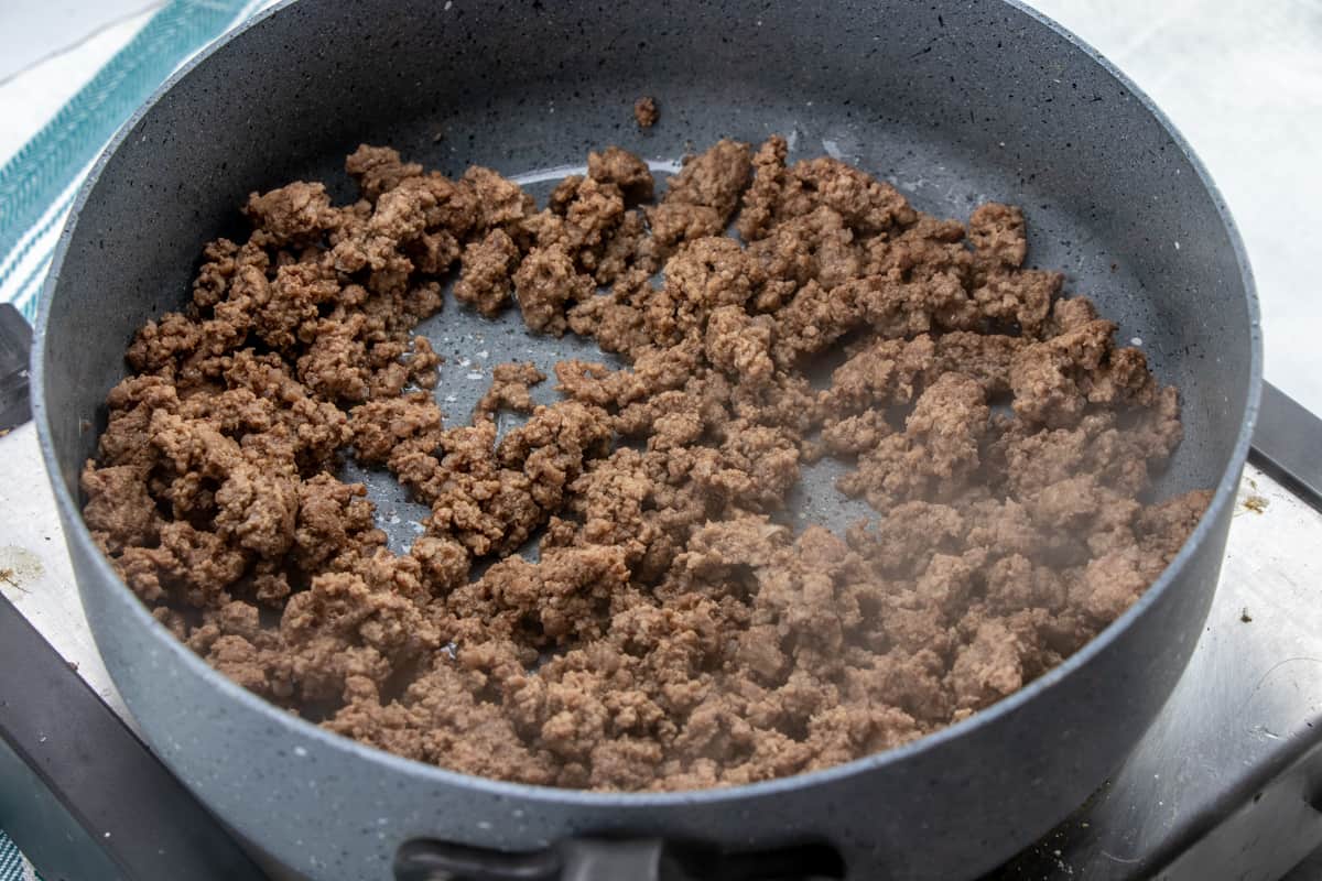browning and crumbling ground beef in a pan on the stovetop.