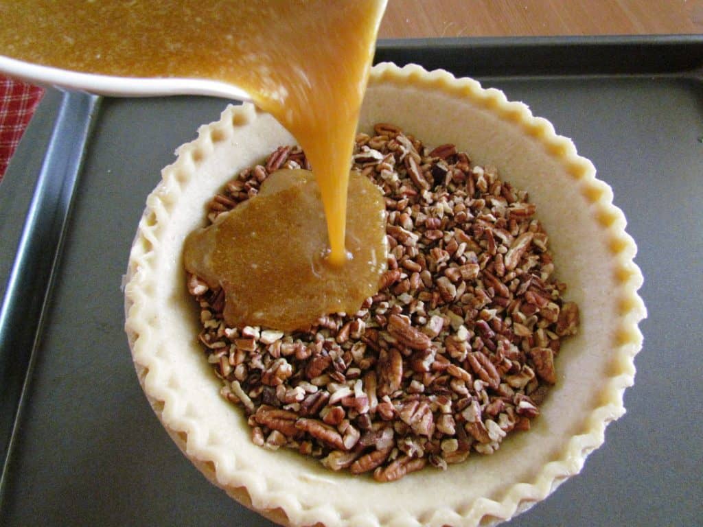 pour pecan pie batter mixture into frozen pie crust filled with chopped pecans