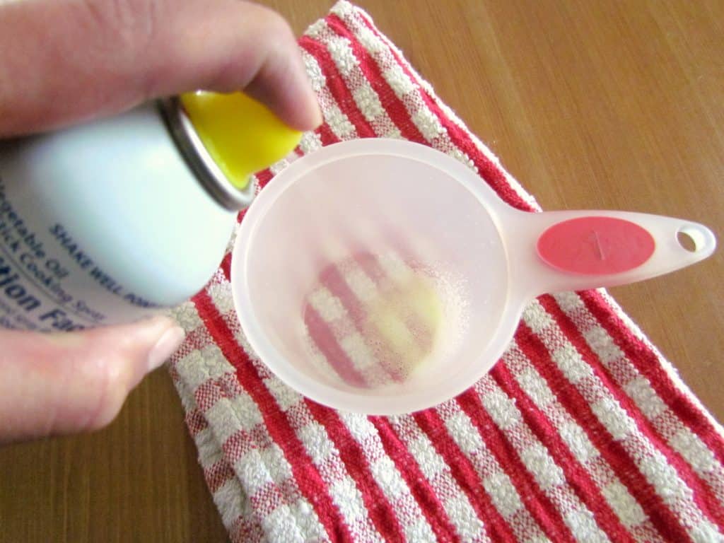 spraying a measuring cup with nonstick cooking spray