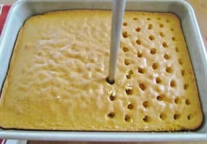poking holes into baked yellow cake