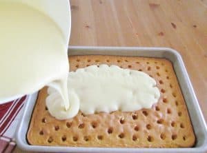 pouring pudding mix over cake with holes in it.