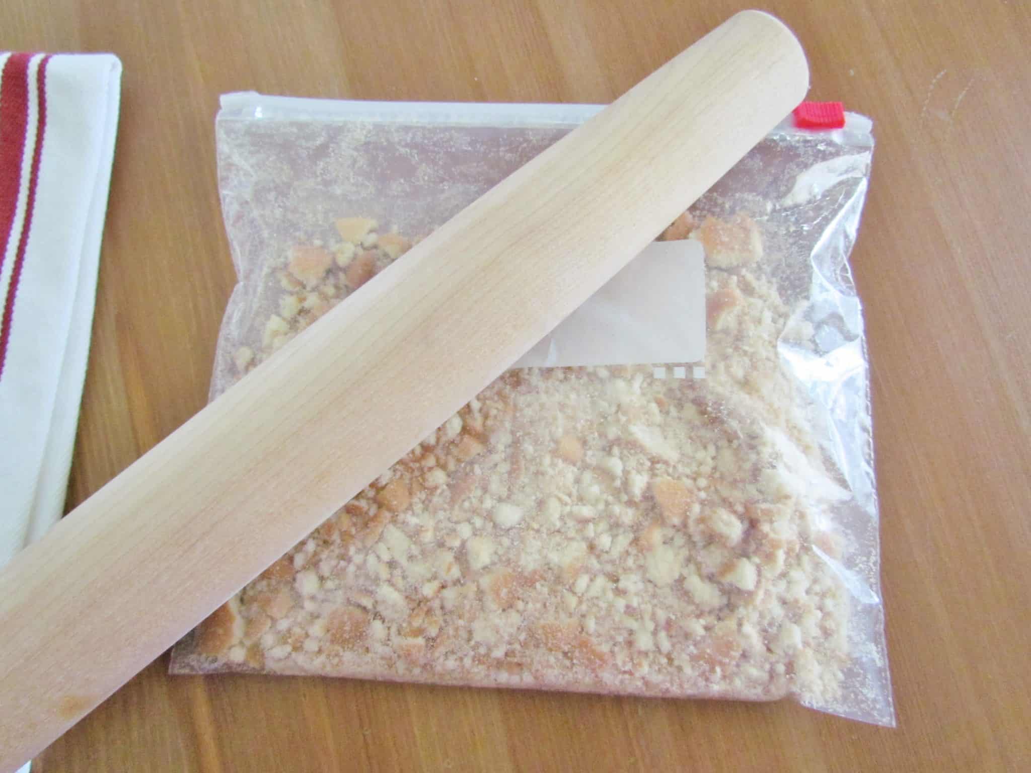 crushing vanilla (Nilla) wafers in a Ziploc bag with a wooden rolling pin.