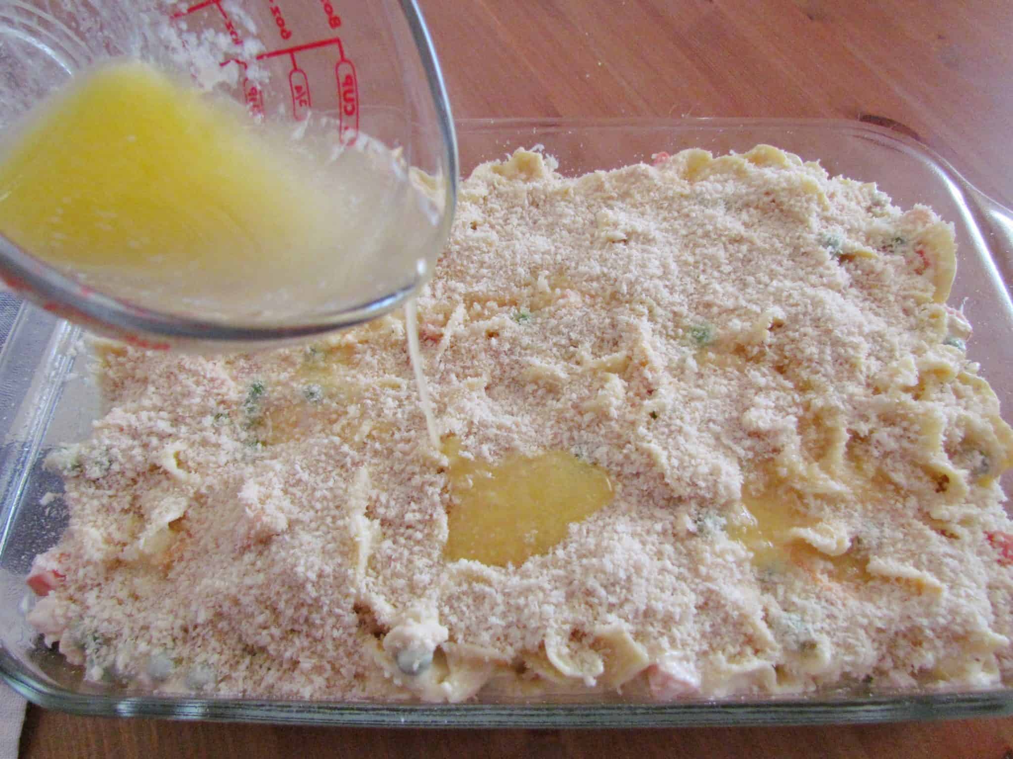 pouring melted butter on top of panko bread crumbs.