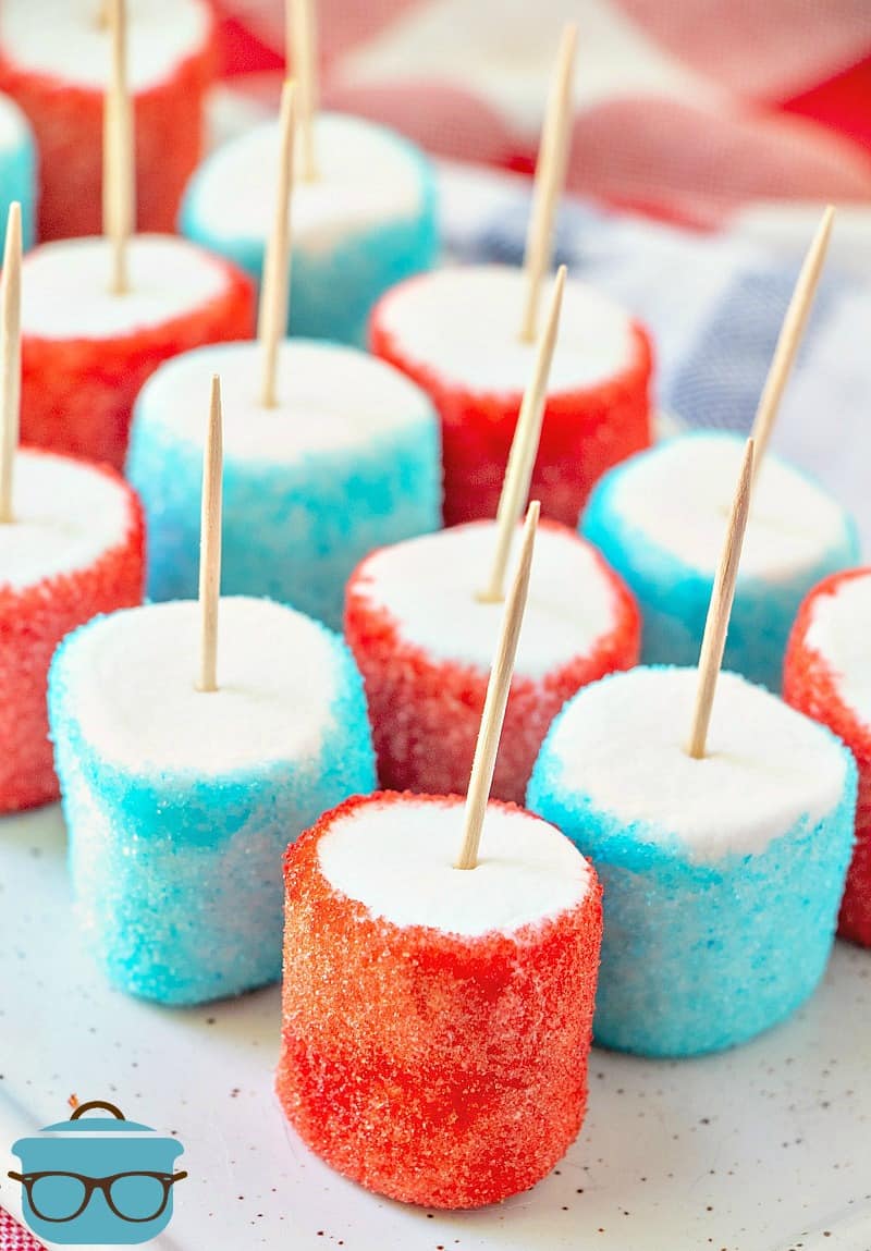 red and blue jell-o dipped marshmallows with toothpicks inserted on a white tray.