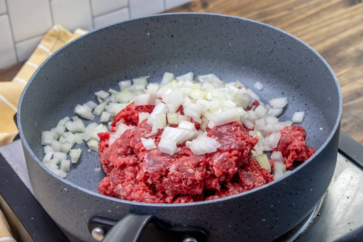 ground beef and diced onion in a large grey skillet.