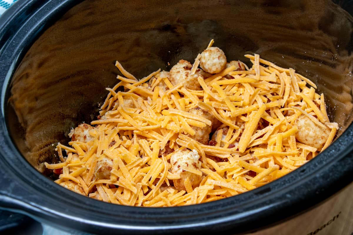 shredded cheddar cheese sprinkled on top of layers in slow cooker