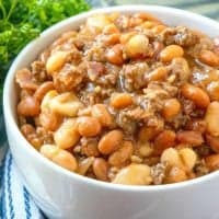 Calico Baked Beans in a white bowl with parsley in the background
