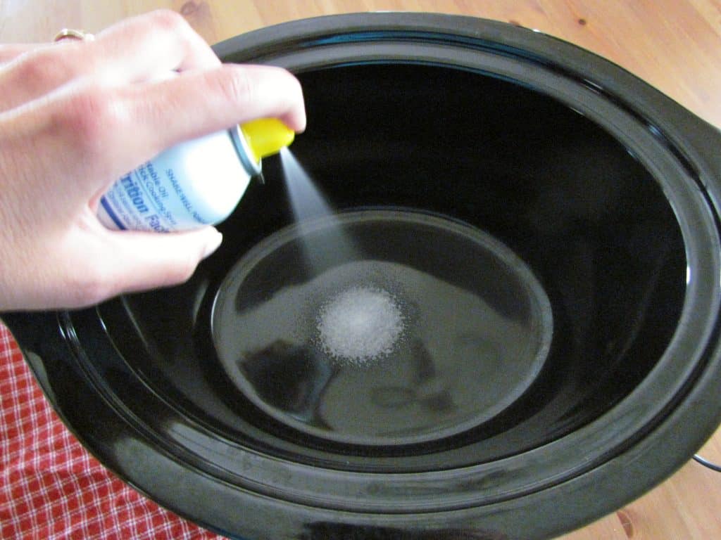 spraying a 6-quart oval crock pot with nonstick cooking spray