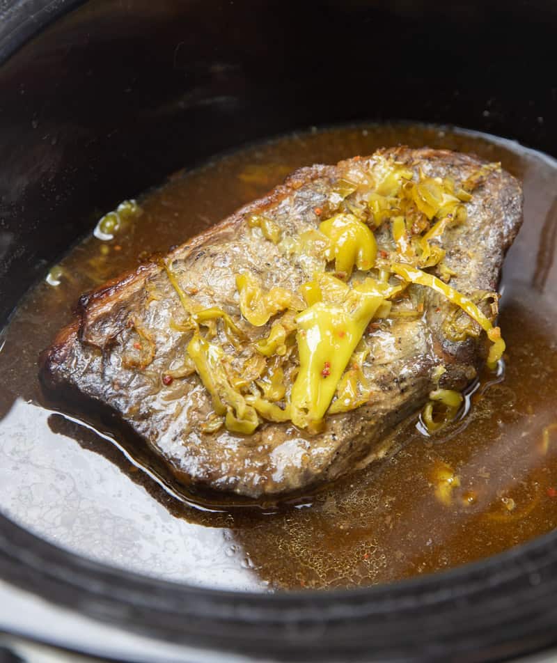 whole chuck roast in a slow cooker with juices