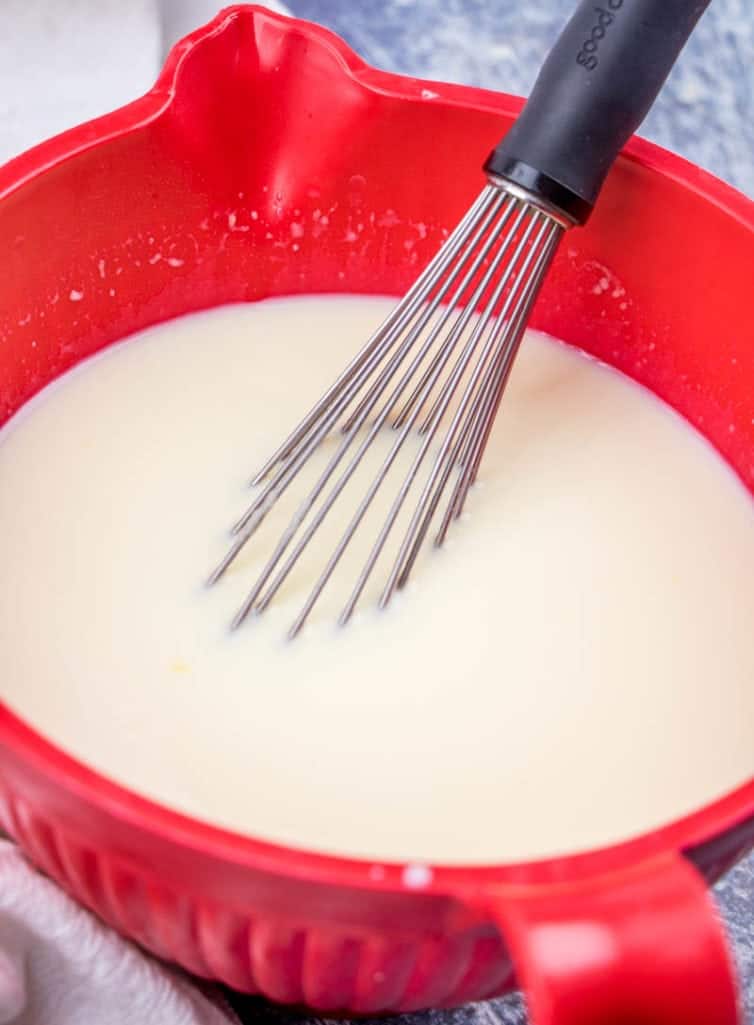prepared cheesecake pudding in a red bowl with a whisk.