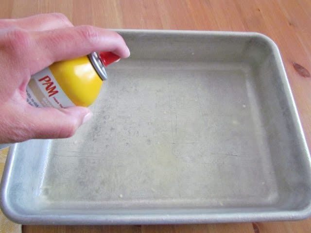 spraying nonstick cooking spray into a baking pan.