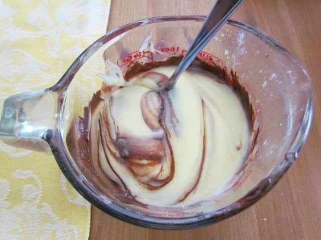 mixing cream cheese mixture and melted chocolate chips in a measuring cup.