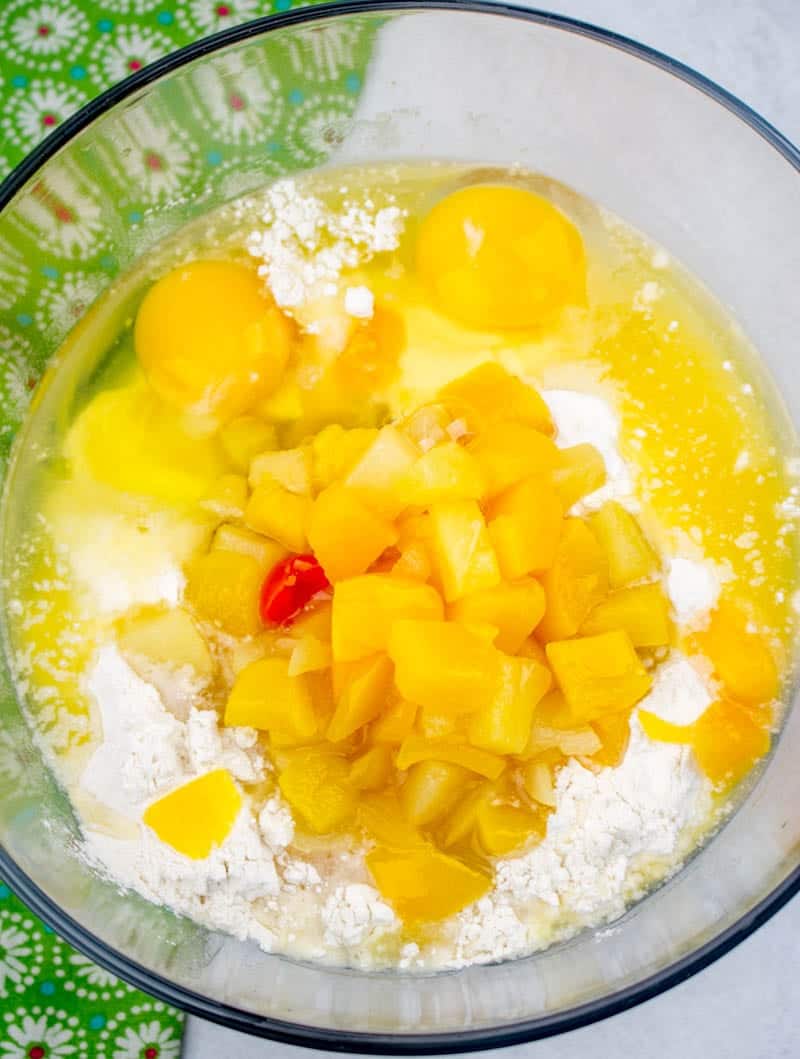 self-rising flour, fruit cocktail in heavy syrup, vanilla extract, sugar and eggs mixed together in a large glass bowl.