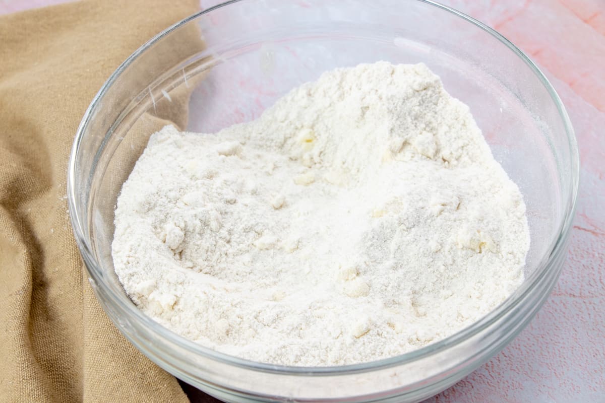 cutting cold butter into all purpose flour, baking powder and sugar in a bowl.