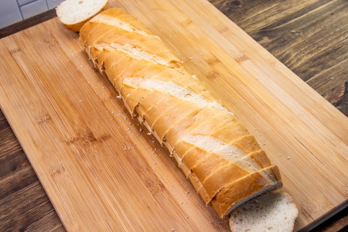 sliced French bread shown on a wooden cutting board
