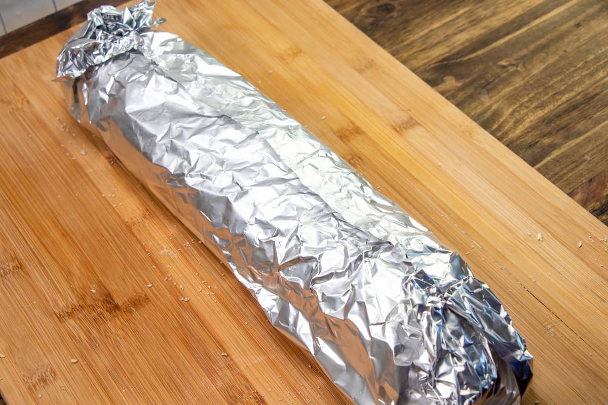bread wrapped in aluminum foil on a wooden board