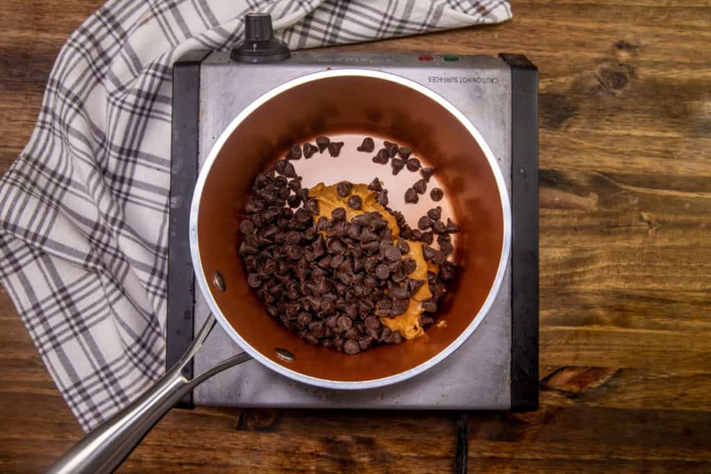 peanut butter and semi-sweet chocolate chips mixed together in a small sauce pot on medium heat