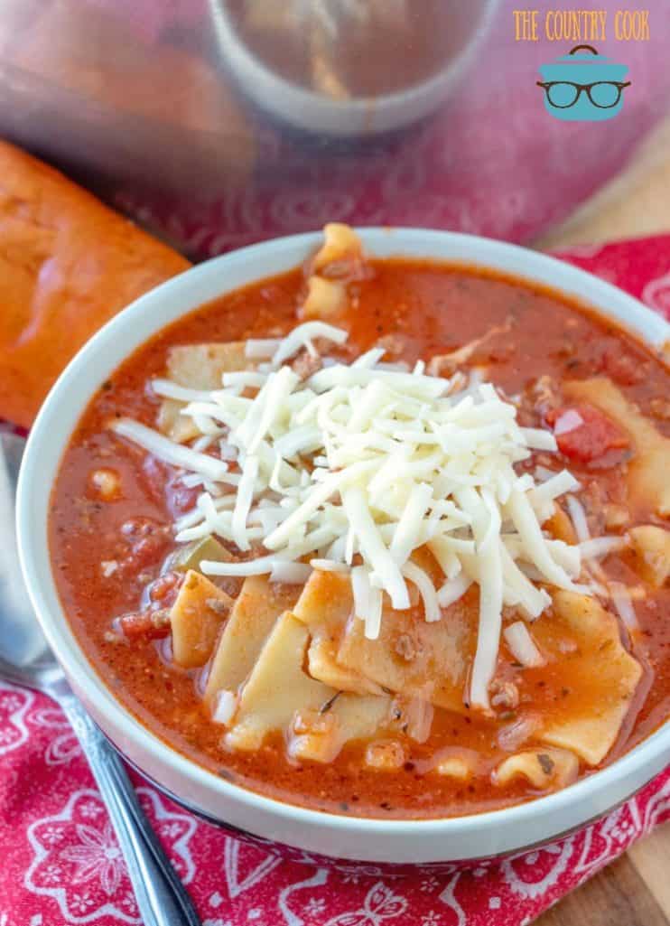 Lasagna Soup in a white bowl with shredded mozzarella on top.