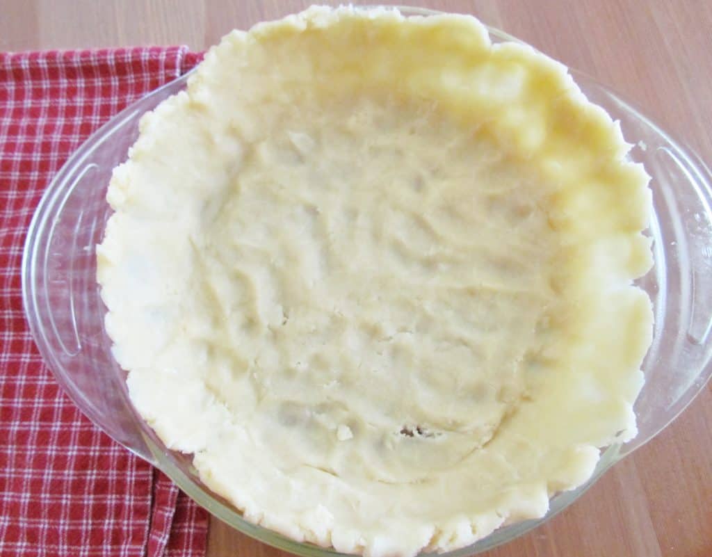 unbaked pie crust shown spread out in the pie dish.