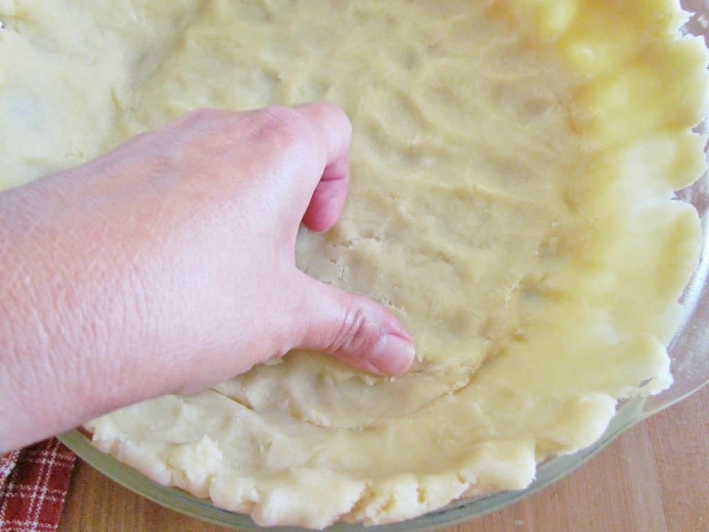 thumb shown pressing the insides of the pie crust to even it out. 