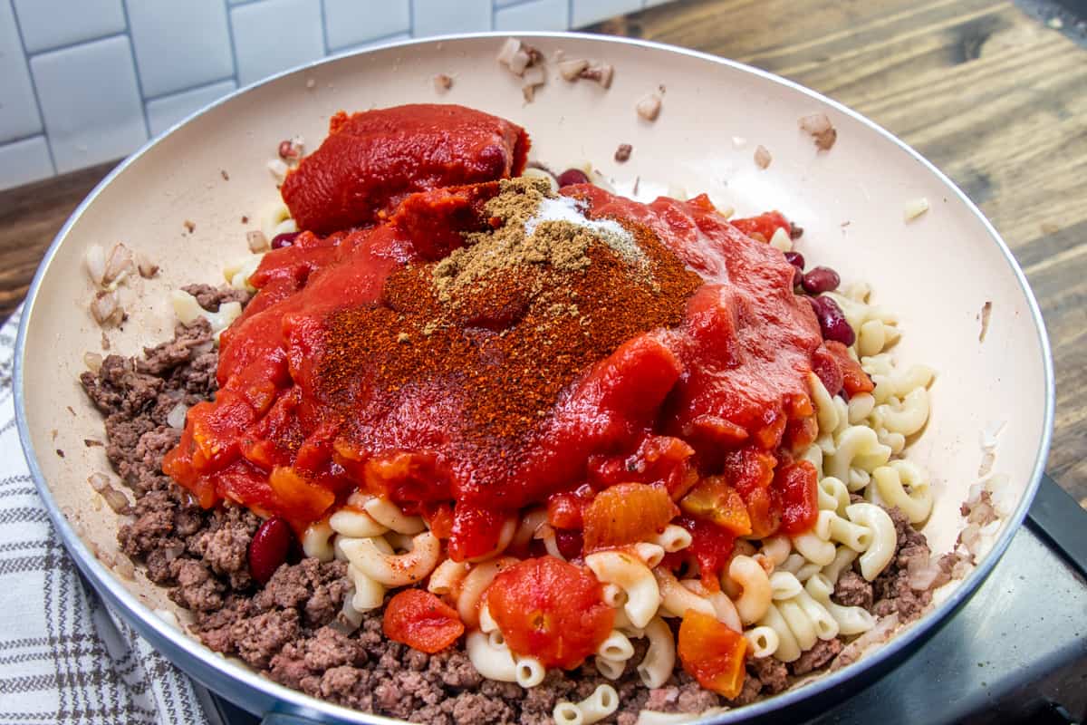 cooked macaroni noodle, tomato sauce, garlic, chili powder and diced tomatoes added to cooked ground beef in the sauce pan.