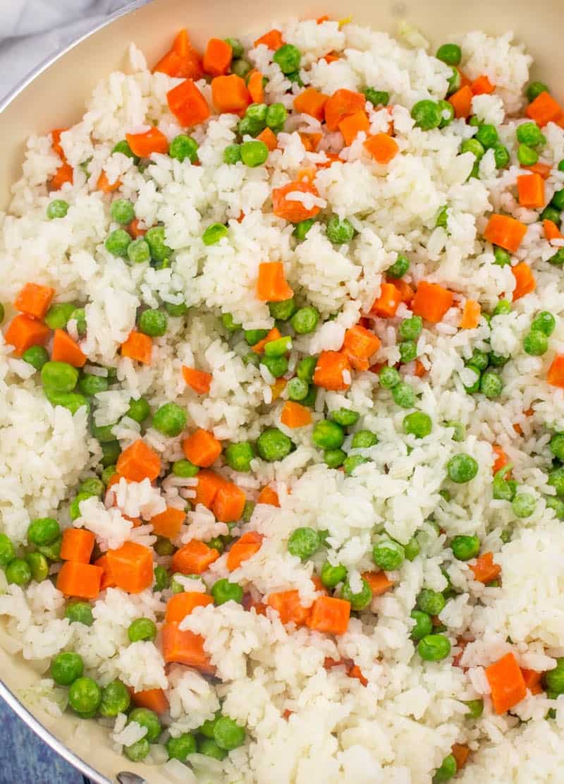 peas and carrots added to cooked rice in a large skillet.