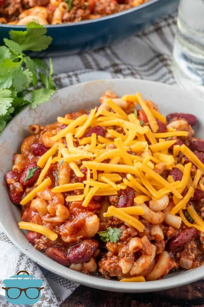 Macaroni chili in a bowl topped with shredded cheese.