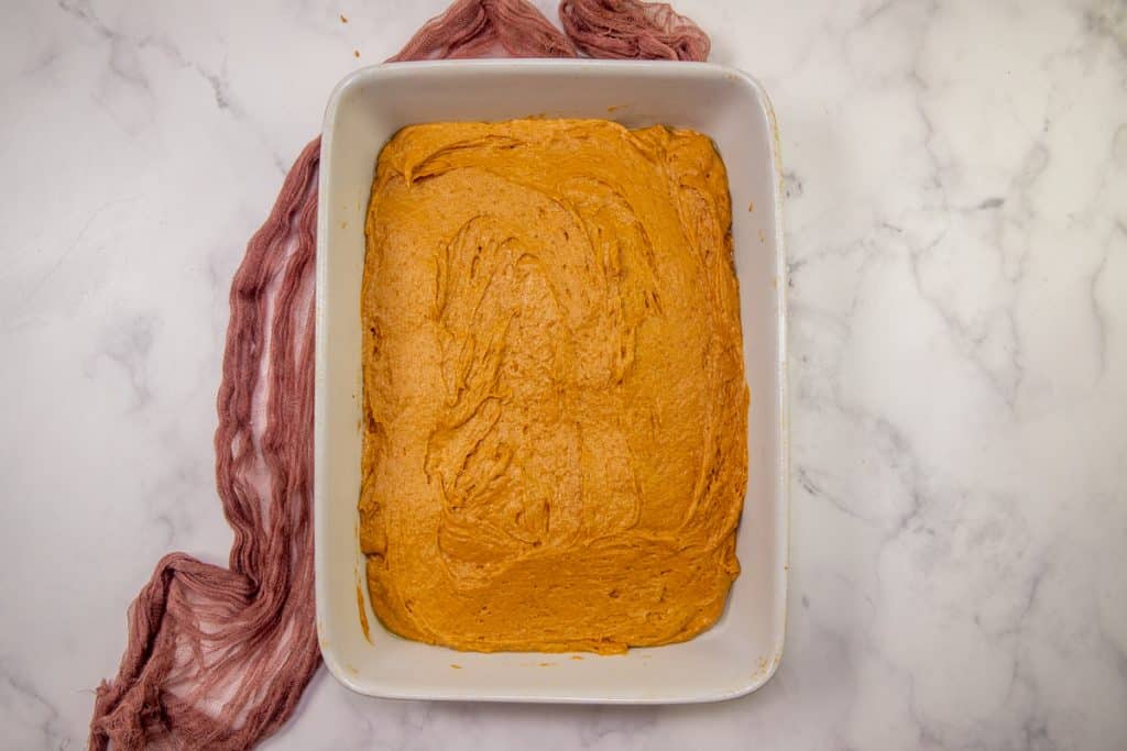 pumpkin spice cake batter spread evenly into a rectangle, white baking dish