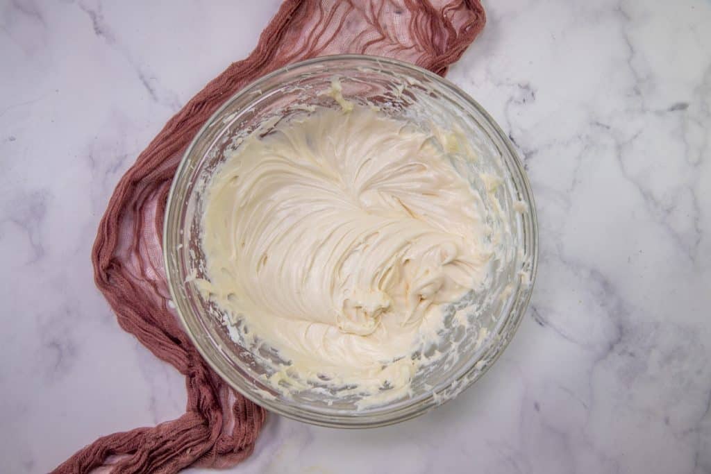 cream cheese frosting, fully mixed, in a clear bowl
