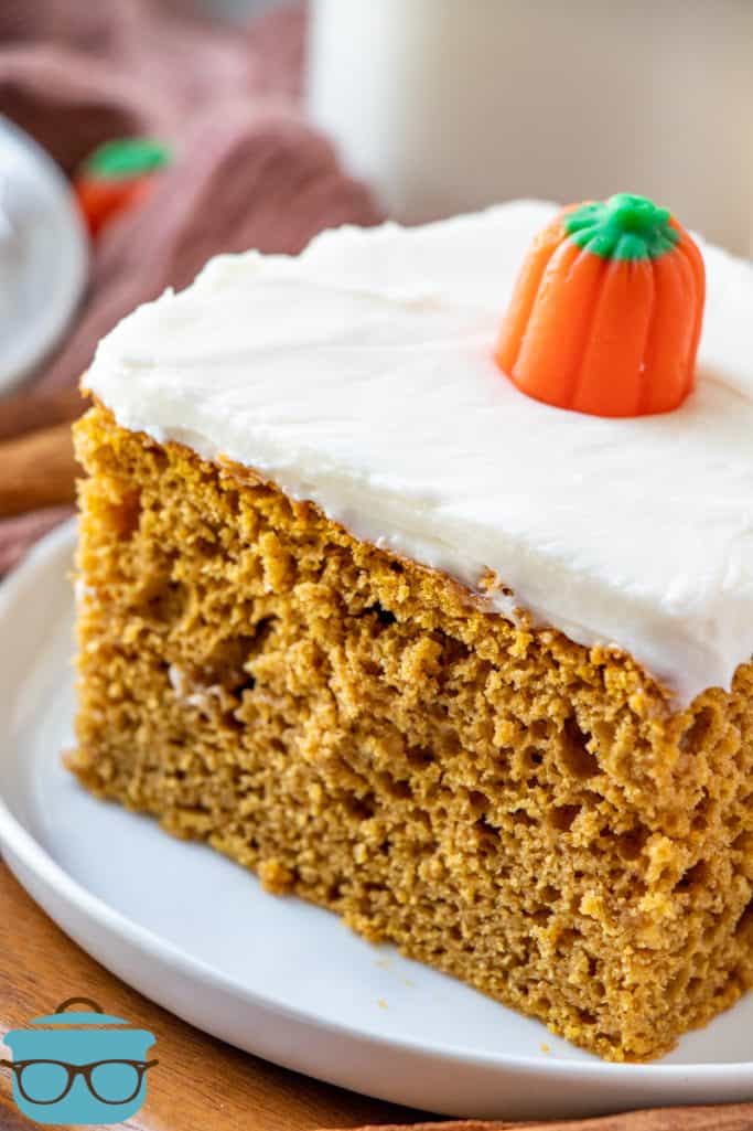 slice of pumpkin spice cake with cream cheee frosting, shown on a small round white plate