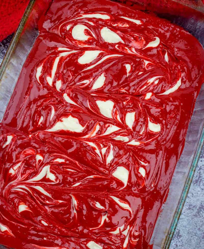 swirled cheesecake batter in red velvet cake batter